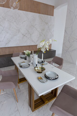 stylish kitchen and a set dining table in a light luxury interior design of a modern apartment in a minimalist style with marble trim and huge windows. daylight inside.