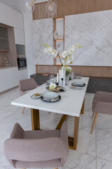 stylish kitchen and a set dining table in a light luxury interior design of a modern apartment in a minimalist style with marble trim and huge windows. daylight inside.