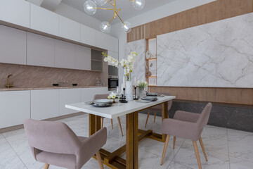 stylish kitchen and a set dining table in a light luxury interior design of a modern apartment in a minimalist style with marble trim and huge windows. daylight inside.