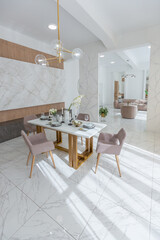 stylish kitchen and a set dining table in a light luxury interior design of a modern apartment in a minimalist style with marble trim and huge windows. daylight inside.