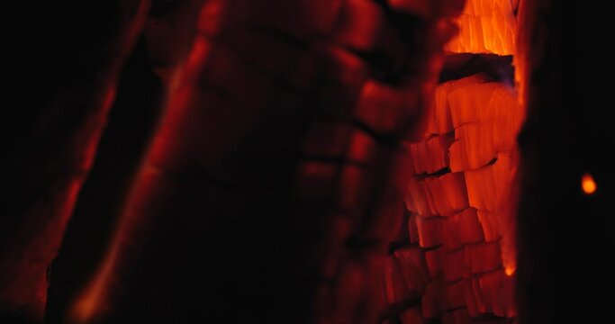 Extreme close-up of a burning hearth. Wooden logs smolder brightly in the fire. Beautiful background with copy space. Bright flames of fire over black background, slow motion 50 fps 4k