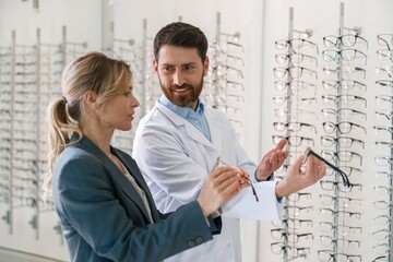 The ophthalmologist helps the client to choose a more suitable spectacle frame in optical store