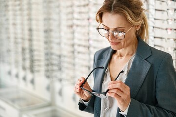 Focused woman inspects a spectacle frame in an optician's shop