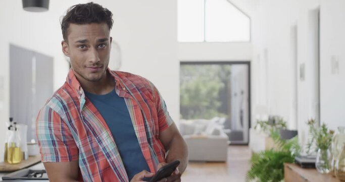 Portrait of happy biracial man in sunny modern apartment using smartphone, copy space, slow motion