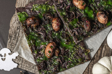 Halloween concept food. Flatbread or pizza with squid Ink, green cheese, mushrooms and purple onion