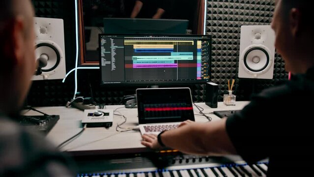 recording studio sound engineer producer mixes songs on screen colorful audio tracks professional music equipment