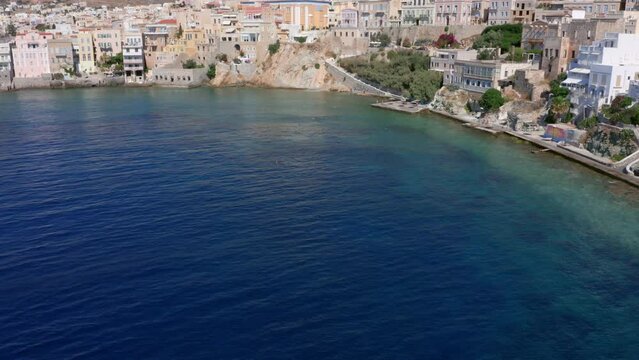 Aerial: Slow panoramic reveal drone shot of Asteria Beach in Ermoupoli of Syros island, Greece on a sunny day