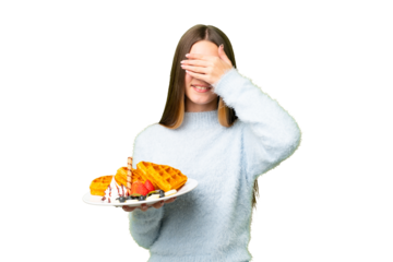 Teenager girl holding waffles over isolated chroma key background covering eyes by hands. Do not want to see something