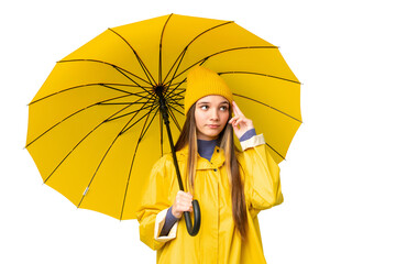 Teenager girl with rainproof coat and umbrella over isolated chroma key background having doubts...