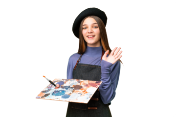 Young artist man holding a palette over isolated chroma key background saluting with hand with happy expression