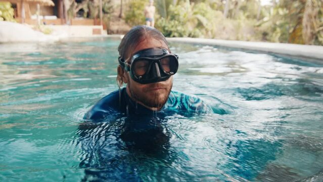 Pool training. Male freediver appears from the water and starts proper recovery breathing after breath hold and swimming underwater