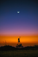 The silhouette of a girl and a motorcycle against the backdrop of a stunning sunset, and a large...