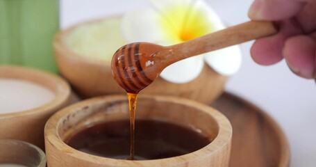 Close up bowl of pure honey mixed for spa therapy. Honey with honey dipper in wooden bowl. Shiny...