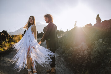 
A beautiful, stylish couple, lovers, a man and a woman, in beautiful clothes posing, spinning, hugging against the background of the mountains.