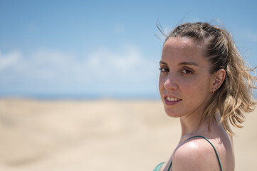 Portrait of a blonde young girl in green dress on the beach dunes