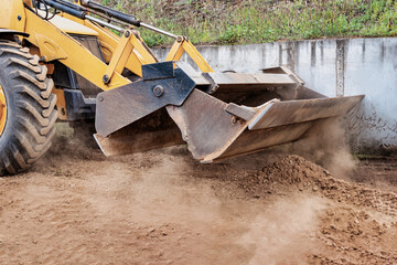 Powerful wheel loader or bulldozer at the construction site. Loader transports sand in a storage...