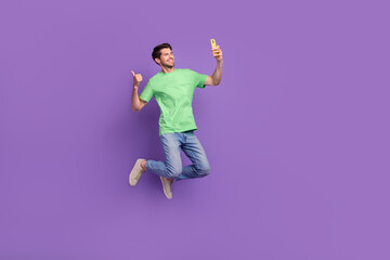 Fototapeta na wymiar Full body photo of jumping guy thumb up activity crazy blogger like sign selfie cadre recording video isolated on violet color background