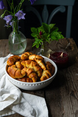 Traditional Ukrainian homemade baked goods: crescents with edible rose jam, and summer flowers  on old wooden table.