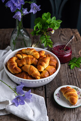 Traditional Ukrainian homemade baked goods: crescents with edible rose jam, and summer flowers  on old wooden table.