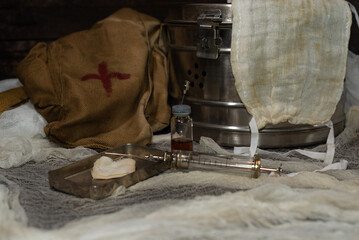 Glass reusable retro syringe on the background of a medical bix and a bag of a military doctor