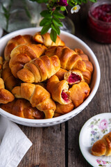 Traditional Ukrainian baked goods. Homemade crescents with edible rose jam on old wooden table.