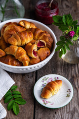 Traditional Ukrainian baked goods. Homemade crescents with edible rose jam on old wooden table.