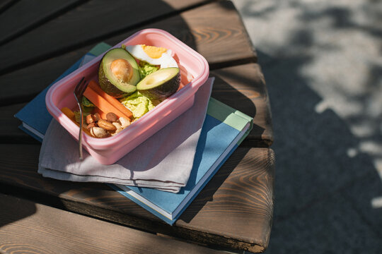 Close-up overhead view of a Lunchbox with eggs, avocado, salad, carrots and nuts