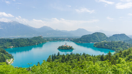 Fototapeta na wymiar Beautiful panorama of the beautiful Bled lake on a sunny day with blue tones on the water and green vegetation surrounding the lake