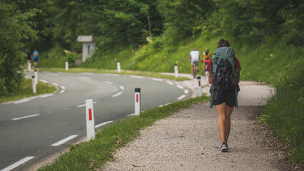 Woman backpacking and walking on a parallel path to the road 