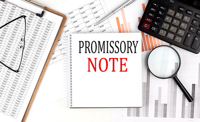 PROMISSORY NOTE text on notebook with clipboard and calculator on a chart background