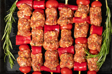 Kebab with vegetables and minced meat. Shish kebab with raw minced meat, pepper and tomato on gray...
