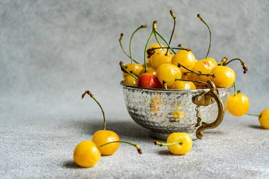 Close-up of a red cherry in a bowl of yellow cherries