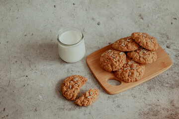 Oatmeal cookies with milk on light background with crumbs