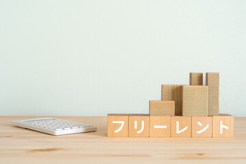 フリーレントと書かれたブロック、電卓、ミニチュアの建物