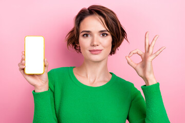 Photo of shiny adorable girl dressed green sweater rising modern device empty space showing okey...