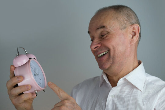 close-up mature man, senior 60 years old holds alarm clock in hand, concept missing time, oversleeping important meeting, life deadline, active SeniorLife, old age crisis, decrease in overall activity