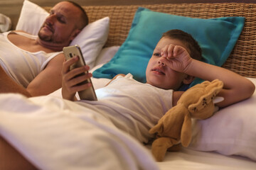 Shot of a Father and son using a smartphone in bed at night.