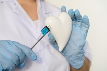 female scientist, doctor holding heart model, microprocessor, microchip, biochip tweezers for...