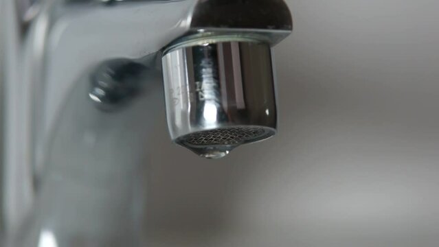 Video Macro de un grifo cromado goteando agua.