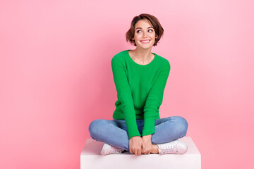 Full length photo of positive cute lady sitting looking up empty space seasonal special offer...