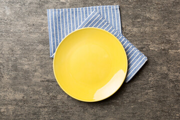 Top view on colored background empty round yellow plate on tablecloth for food. Empty dish on napkin with space for your design