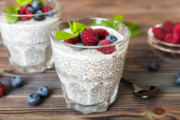 Healthy breakfast or morning with chia seeds vanilla pudding raspberry and blueberry berries on table background, vegetarian food, diet and health concept. Chia pudding with raspberry and blueberry