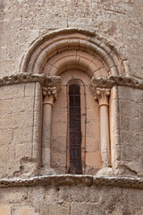 small romanesque window with small columns and corinthian capitals in the apse of a church