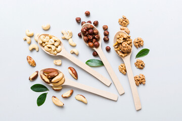 mixed nuts in white wooden spoon. Mix of various nuts on colored background. pistachios, cashews, walnuts, hazelnuts, peanuts and brazil nuts