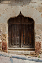 old wooden door with ogee arch in a stone facade of an old building