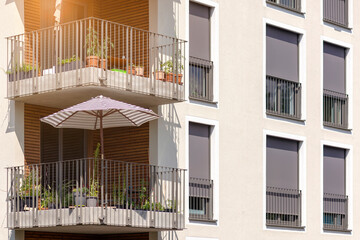 Fototapeta premium Sun Protection of Modern Apartment Bilding with External Roller Blinds or Shutters Outside, Sun Umbrella on Solar Balcony.