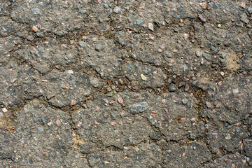 A network of black cracks on the asphalt surface. Road texture with weathered surface, showcasing the effects of time and wear