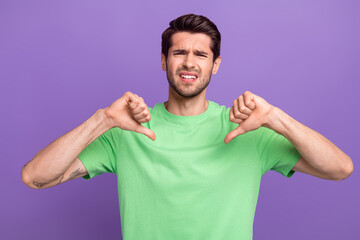 Portrait of young man wear trendy green t-shirt direct fingers himself dissatisfied dislike thumbs...