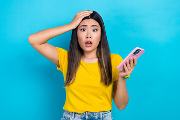 Naklejka premium Portrait of astonished woman dyed hairstyle wear stylish t-shirt arm on head staring hold smartphone isolated on blue color background