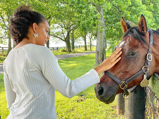 African American female young adult visiting horse at fence in Central Kentucky
